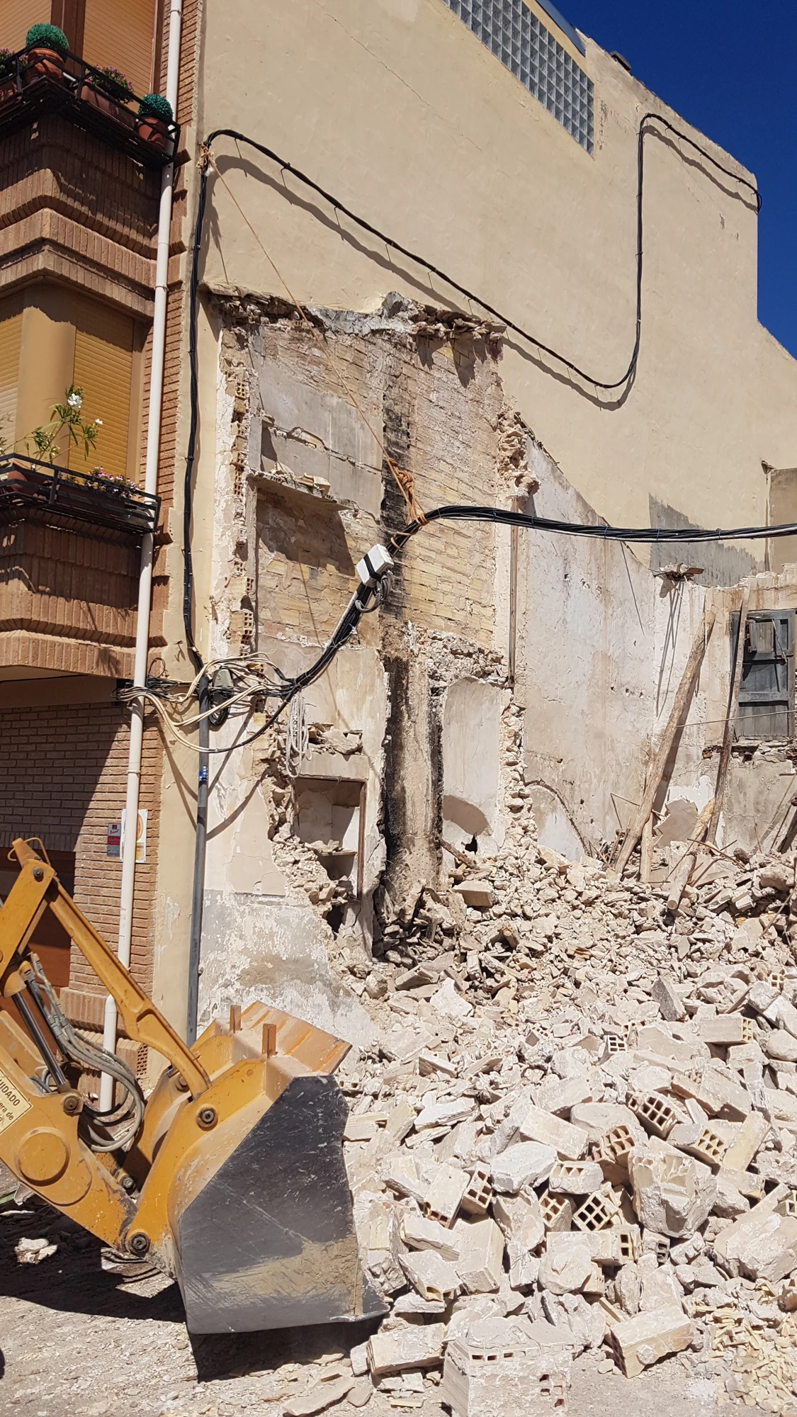 Maquinaria y escombros durante la demolición junto a las edificaciones colindantes